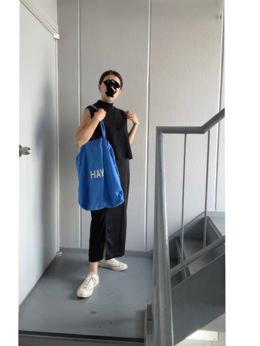 ブラック系のスカート、ホワイト系のスニーカー、ブルー系のトートバッグを着用したレディースの秋コーディネートの3枚目の写真