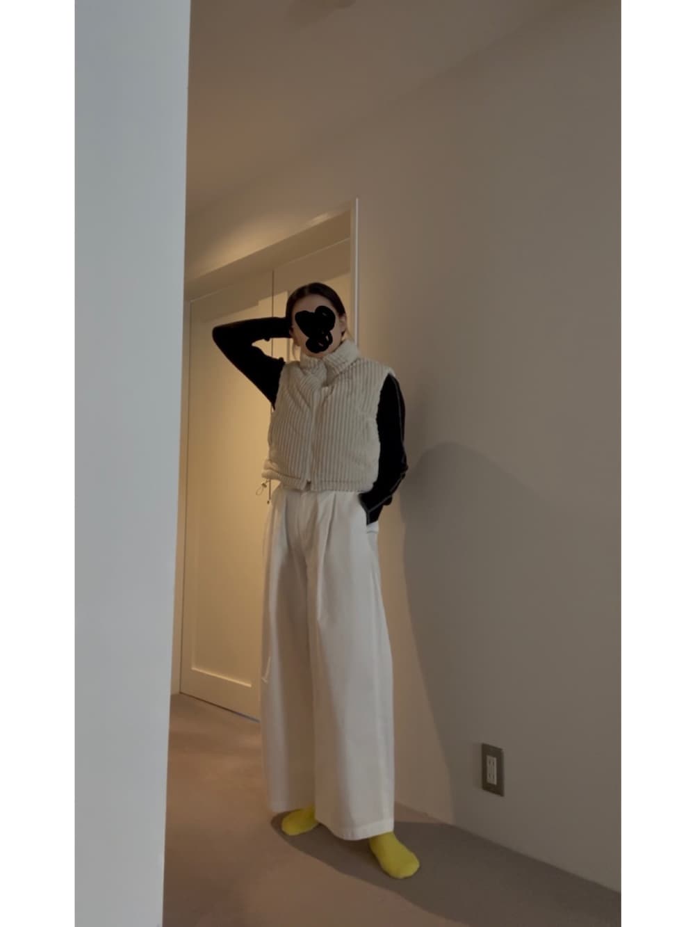 ホワイト系のベスト、ブラック系のニット/セーター、ブルー系のスニーカーを着用したレディースの春コーディネートの2枚目の写真