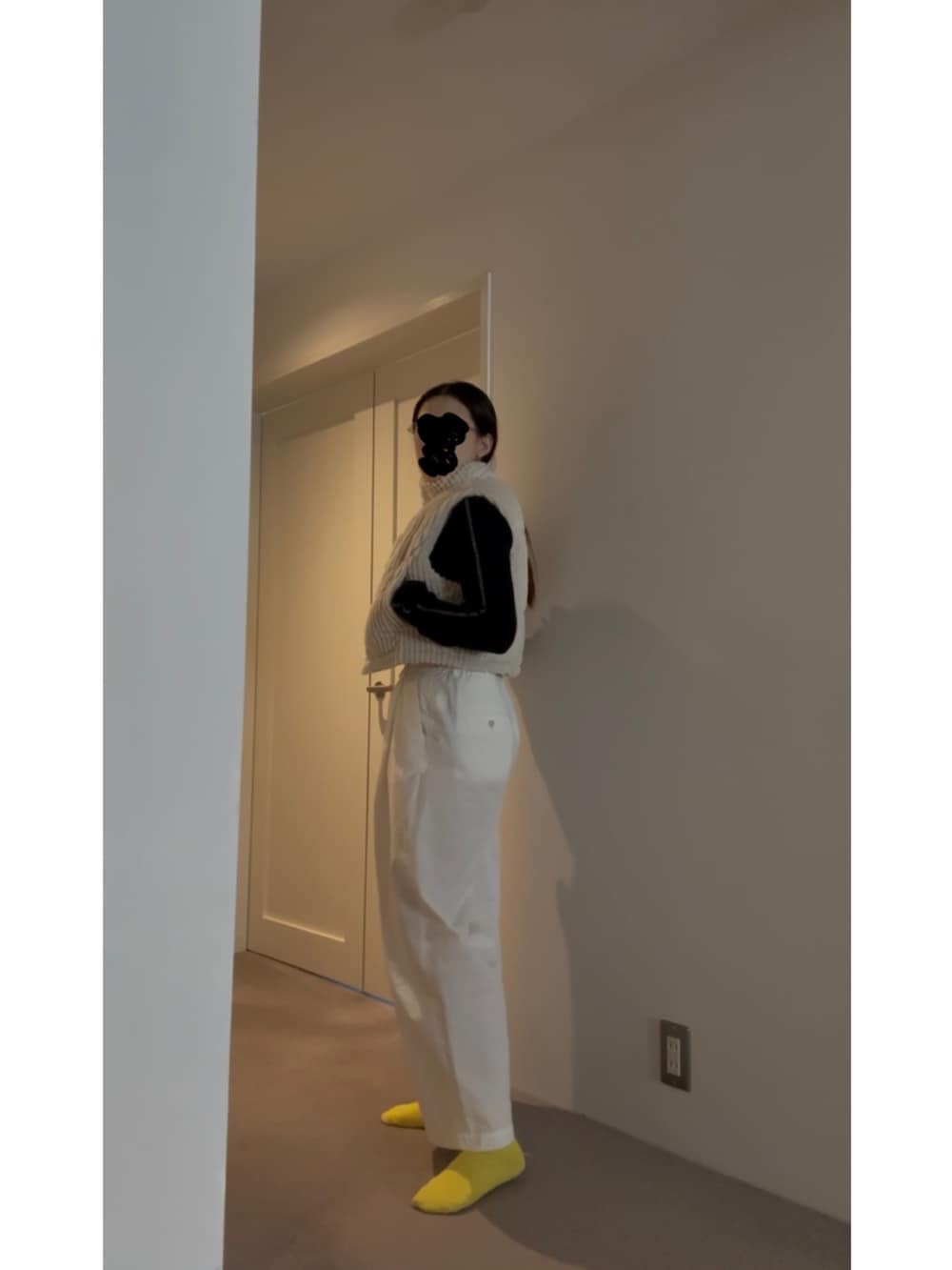 ホワイト系のベスト、ブラック系のニット/セーター、ブルー系のスニーカーを着用したレディースの春コーディネートの5枚目の写真