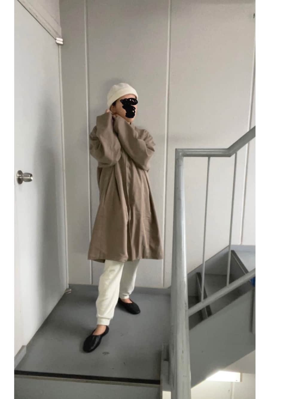 ブラウン系のステンカラーコート、ホワイト系のパンツ、ベージュ系のニットキャップ/ビーニーを着用したレディースの秋コーディネートの5枚目の写真