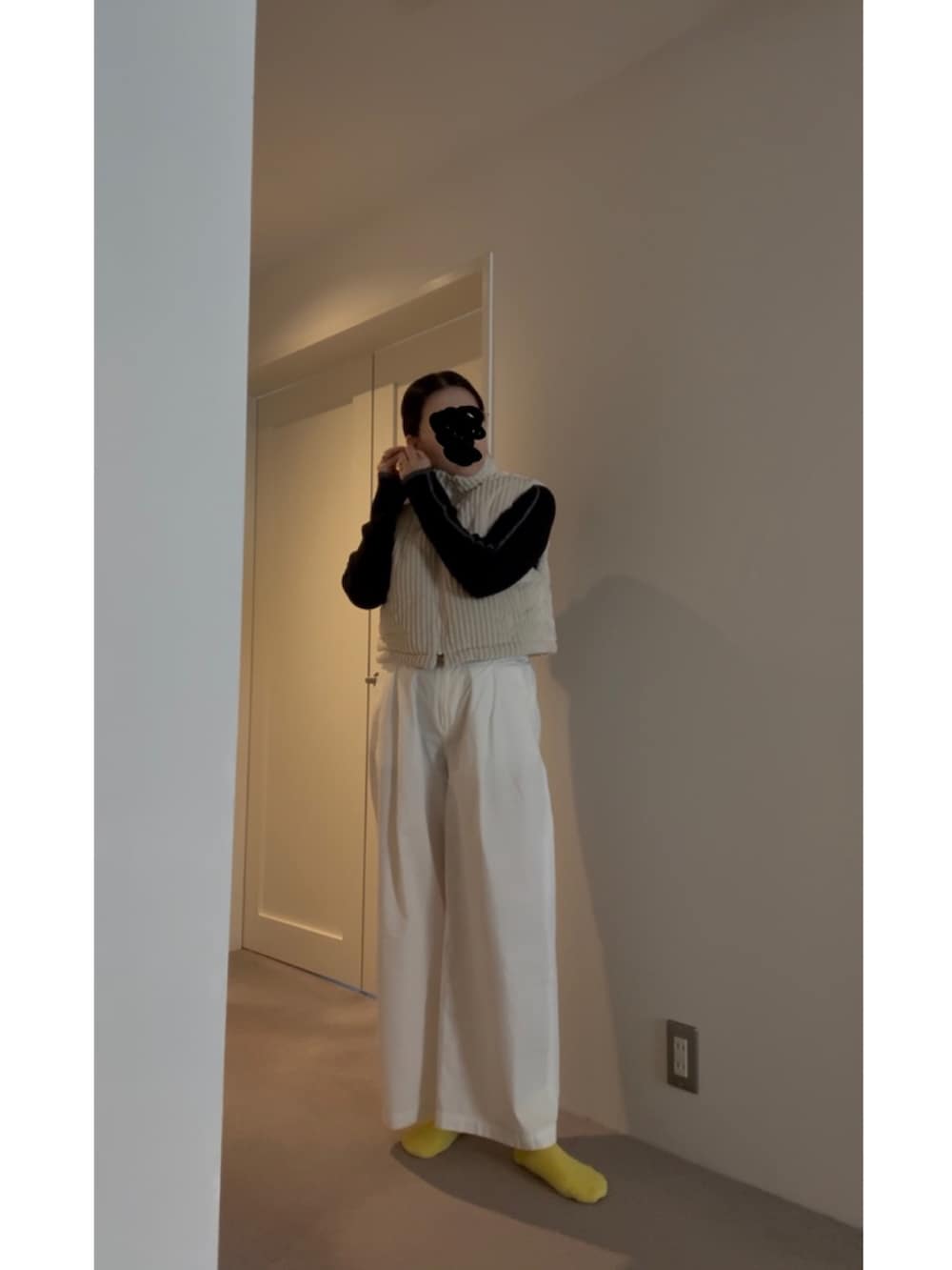 ホワイト系のベスト、ブラック系のニット/セーター、ブルー系のスニーカーを着用したレディースの春コーディネートの4枚目の写真