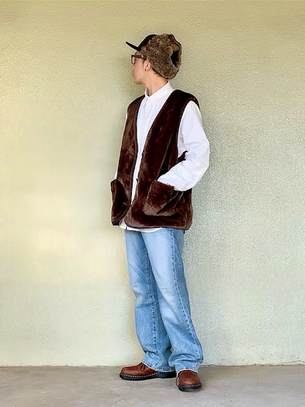 ブラウン系のベスト、ベージュ系のトレンチコート、ブルー系のデニムパンツを着用したメンズの秋コーディネートの3枚目の写真