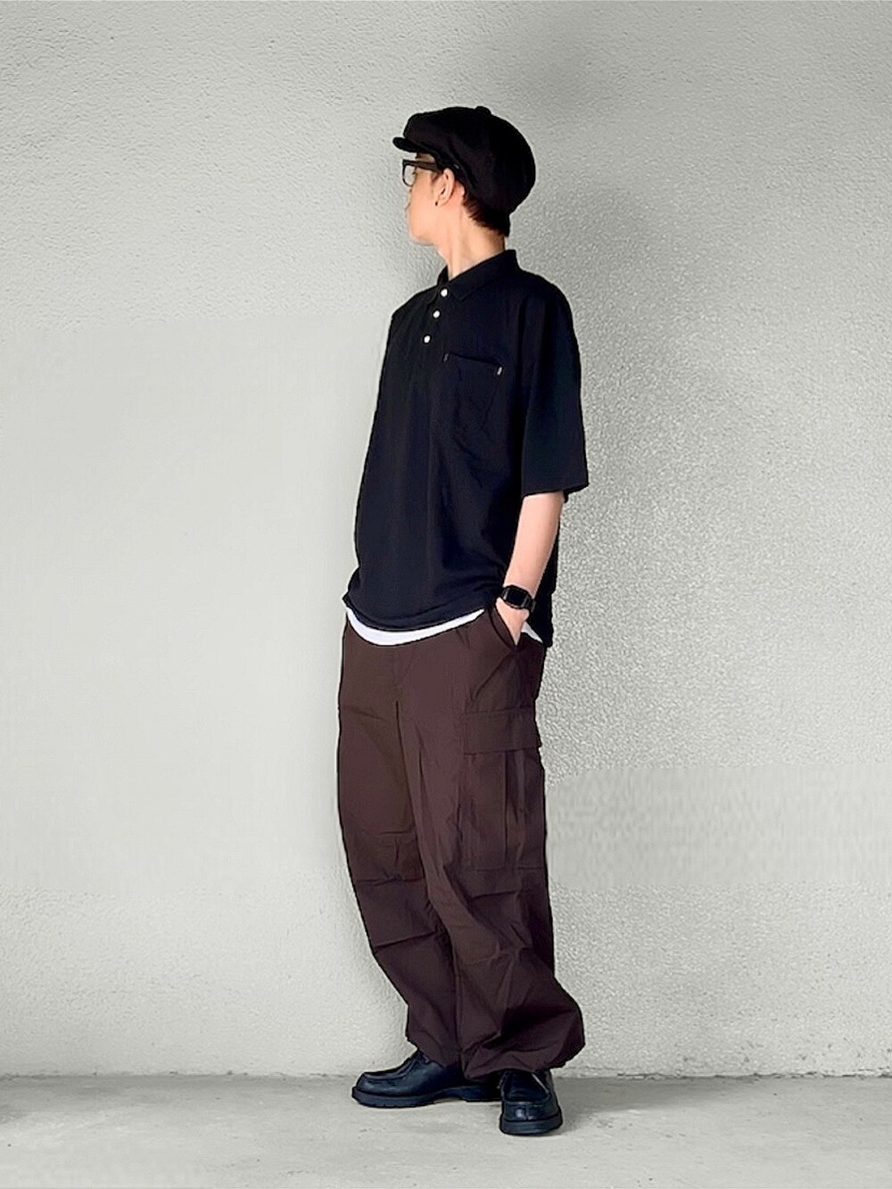 ブラック系のポロシャツ、ブラウン系のカーゴパンツ、ブラック系のドレスシューズを着用したメンズの夏コーディネートの2枚目の写真