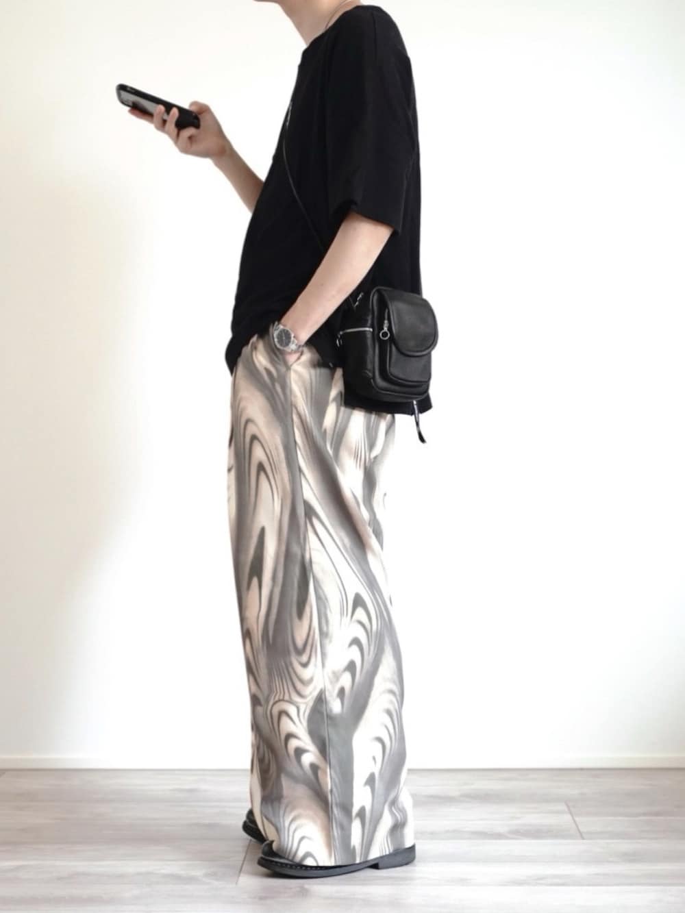 ブラック系のTシャツ/カットソー、ブラック系のバッグ、グリーン系のスラックスを着用したメンズの夏コーディネートの4枚目の写真