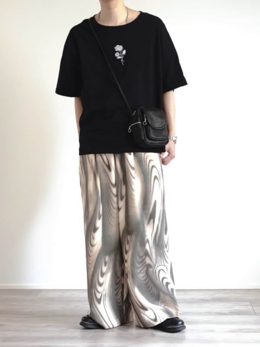 ブラック系のTシャツ/カットソー、ブラック系のバッグ、グリーン系のスラックスを着用したメンズの夏コーディネートの2枚目の写真