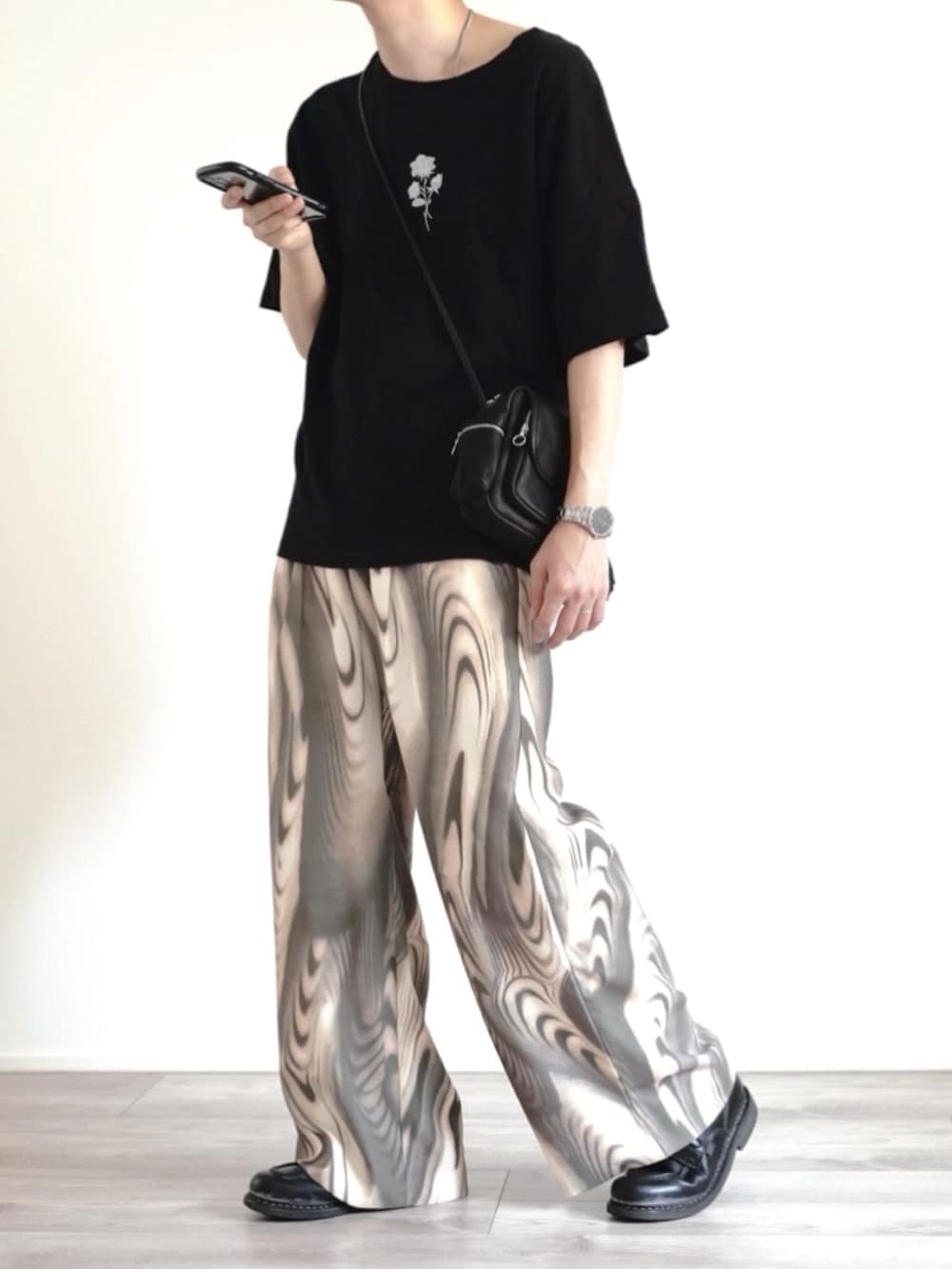 ブラック系のTシャツ/カットソー、ブラック系のバッグ、グリーン系のスラックスを着用したメンズの夏コーディネートの3枚目の写真