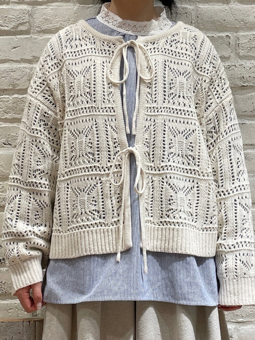 ブルー系のシャツ/ブラウス、ホワイト系のニット/セーター、ベージュ系のスカートを着用したレディースの冬コーディネートの2枚目の写真