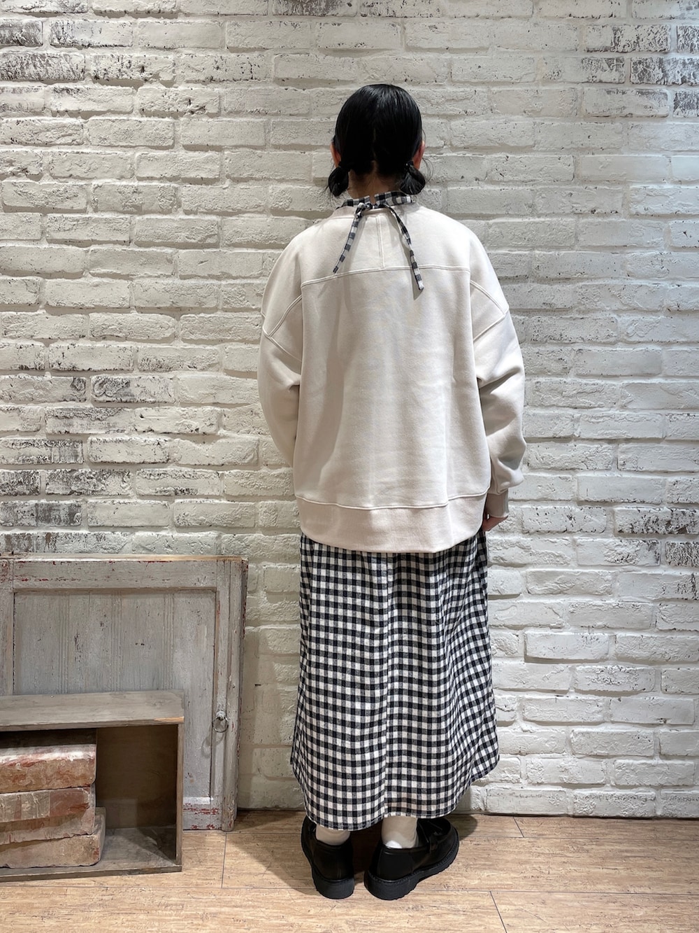 グレー系のハンドバッグ、ブラウン系のローファー、ホワイト系のワンピースを着用したレディースの冬コーディネートの3枚目の写真