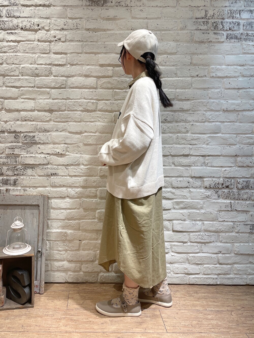 ベージュ系のワンピース、ブラウン系のハンドバッグ、ブラック系のスニーカーを着用したレディースの秋コーディネートの2枚目の写真