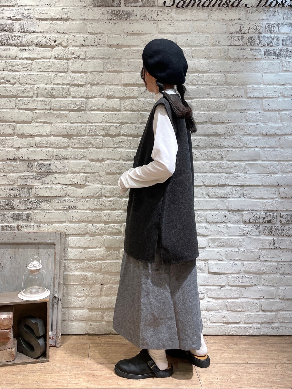 ブラウン系のベスト、グレー系のワンピース、ブラック系のハンドバッグを着用したレディースの秋コーディネートの4枚目の写真