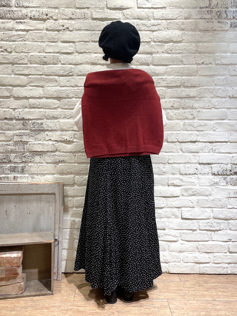 ホワイト系のチュニック、レッド系のカーディガン/ボレロ、ブラック系のスカートを着用したレディースの秋コーディネートの3枚目の写真