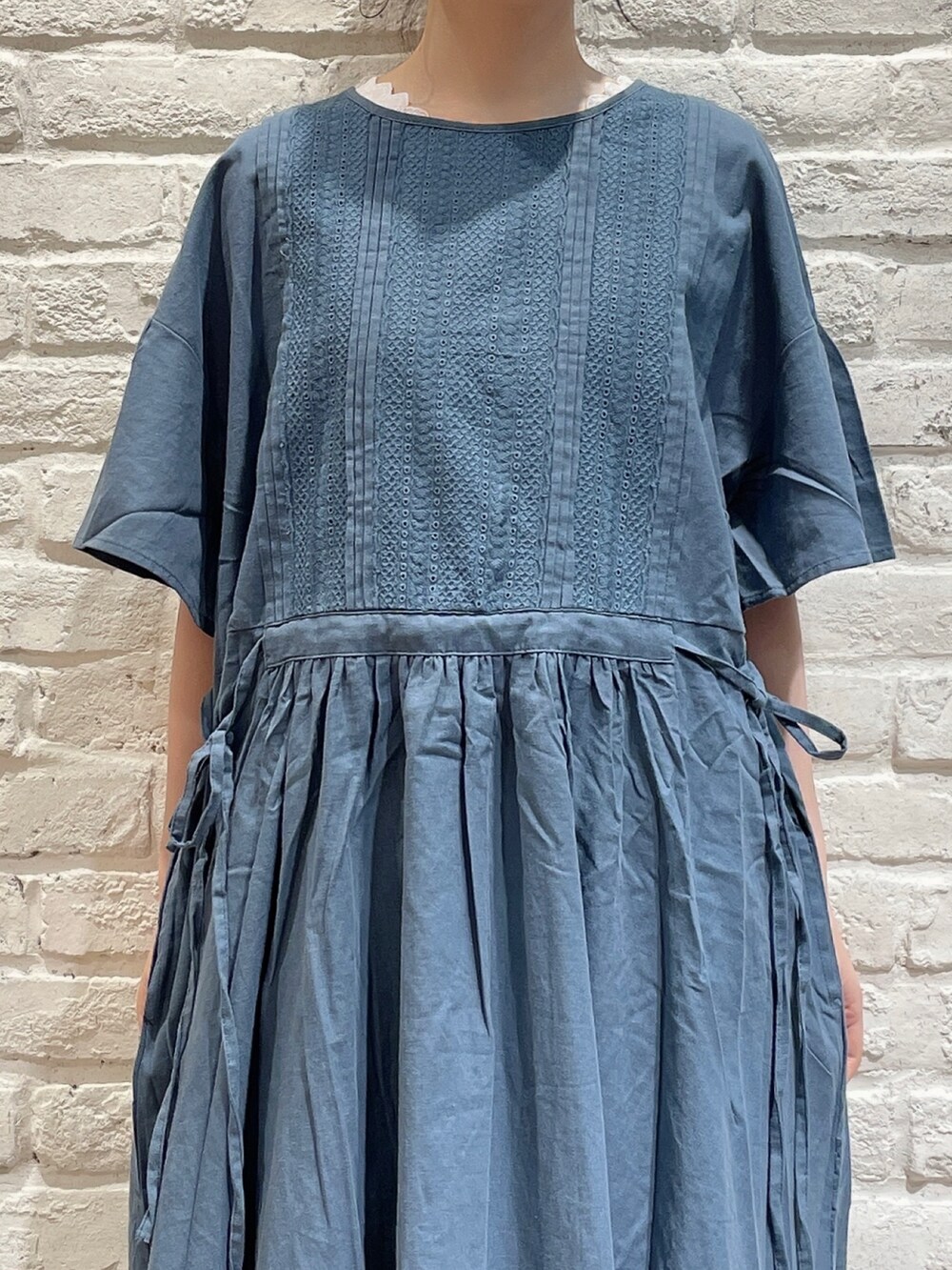 ベージュ系のトートバッグ、グリーン系のワンピース、ホワイト系のTシャツ/カットソーを着用したレディースの夏コーディネートの2枚目の写真