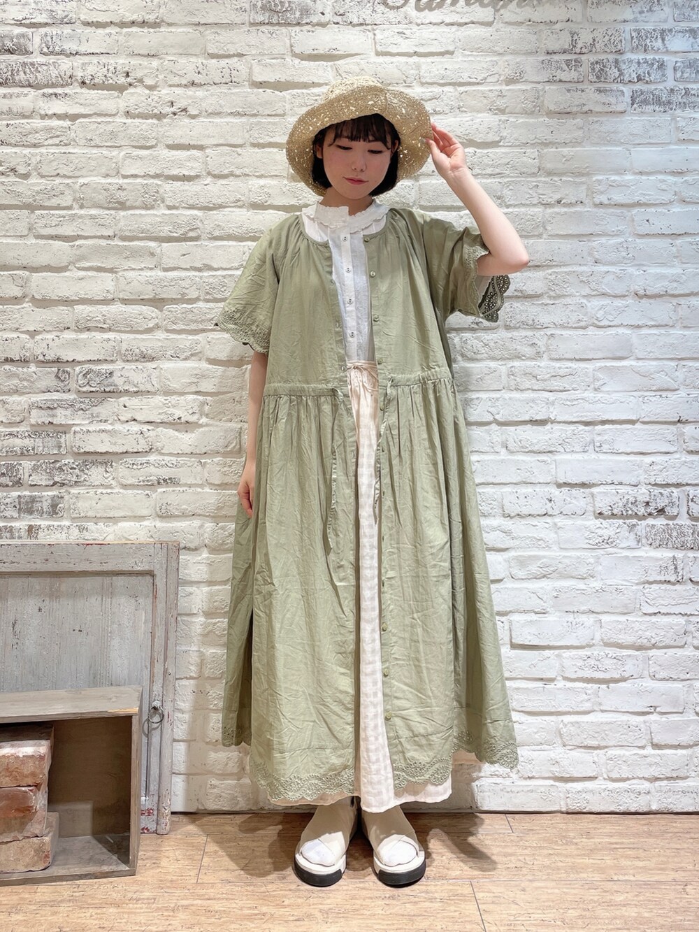 ベージュ系のトートバッグ、ホワイト系のサンダル、グリーン系のワンピースを着用したレディースの夏コーディネートの4枚目の写真