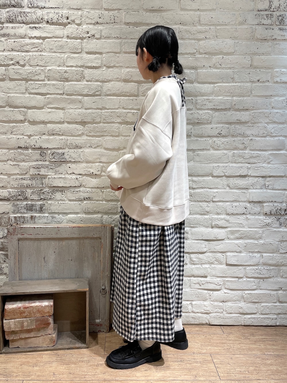 グレー系のハンドバッグ、ブラウン系のローファー、ホワイト系のワンピースを着用したレディースの冬コーディネートの2枚目の写真