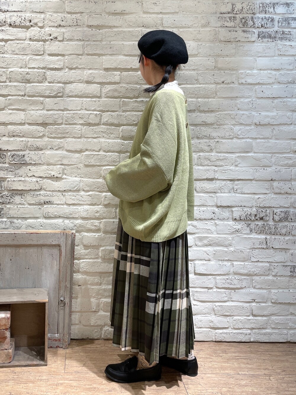 ホワイト系のシャツ/ブラウス、グリーン系のニット/セーター、ブルー系のスカートを着用したレディースの冬コーディネートの2枚目の写真