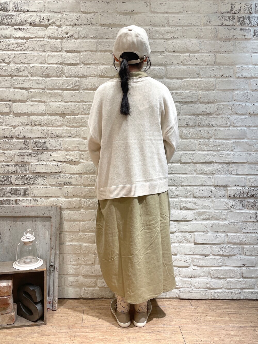 ベージュ系のワンピース、ブラウン系のハンドバッグ、ブラック系のスニーカーを着用したレディースの秋コーディネートの3枚目の写真