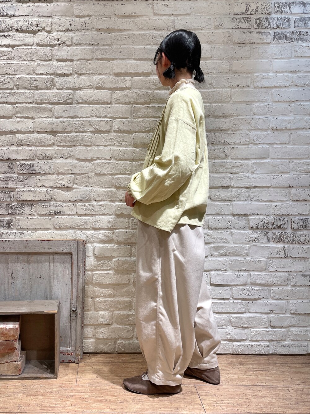 ホワイト系のニット/セーター、イエロー系のシャツ/ブラウス、ブラウン系のハンドバッグを着用したレディースの冬コーディネートの2枚目の写真