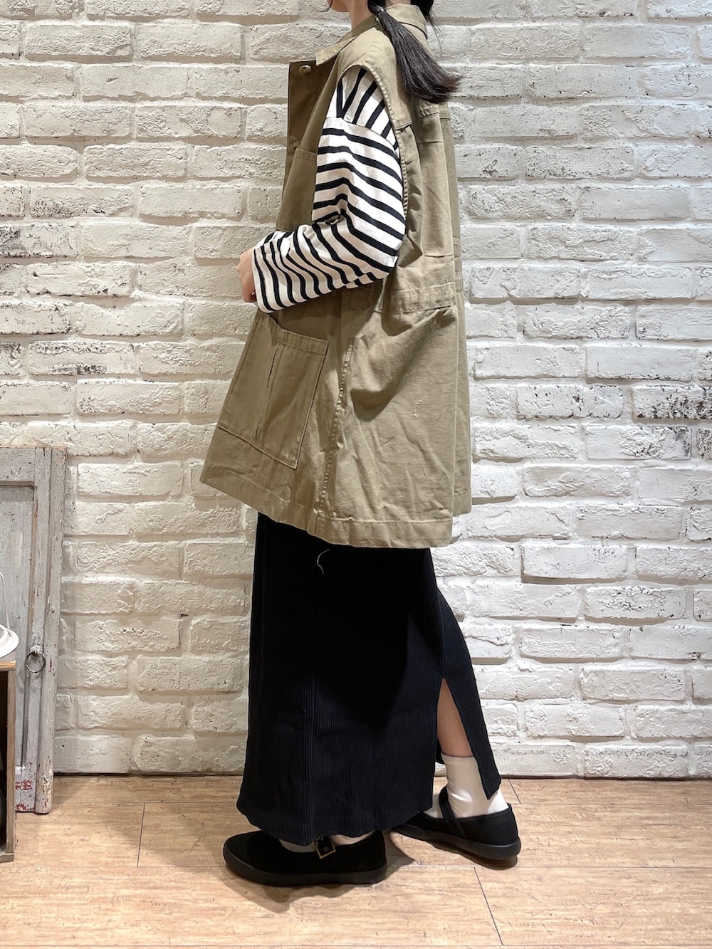 ベージュ系のベスト、ホワイト系のTシャツ/カットソー、ブラック系のスカートを着用したレディースの秋コーディネートの2枚目の写真