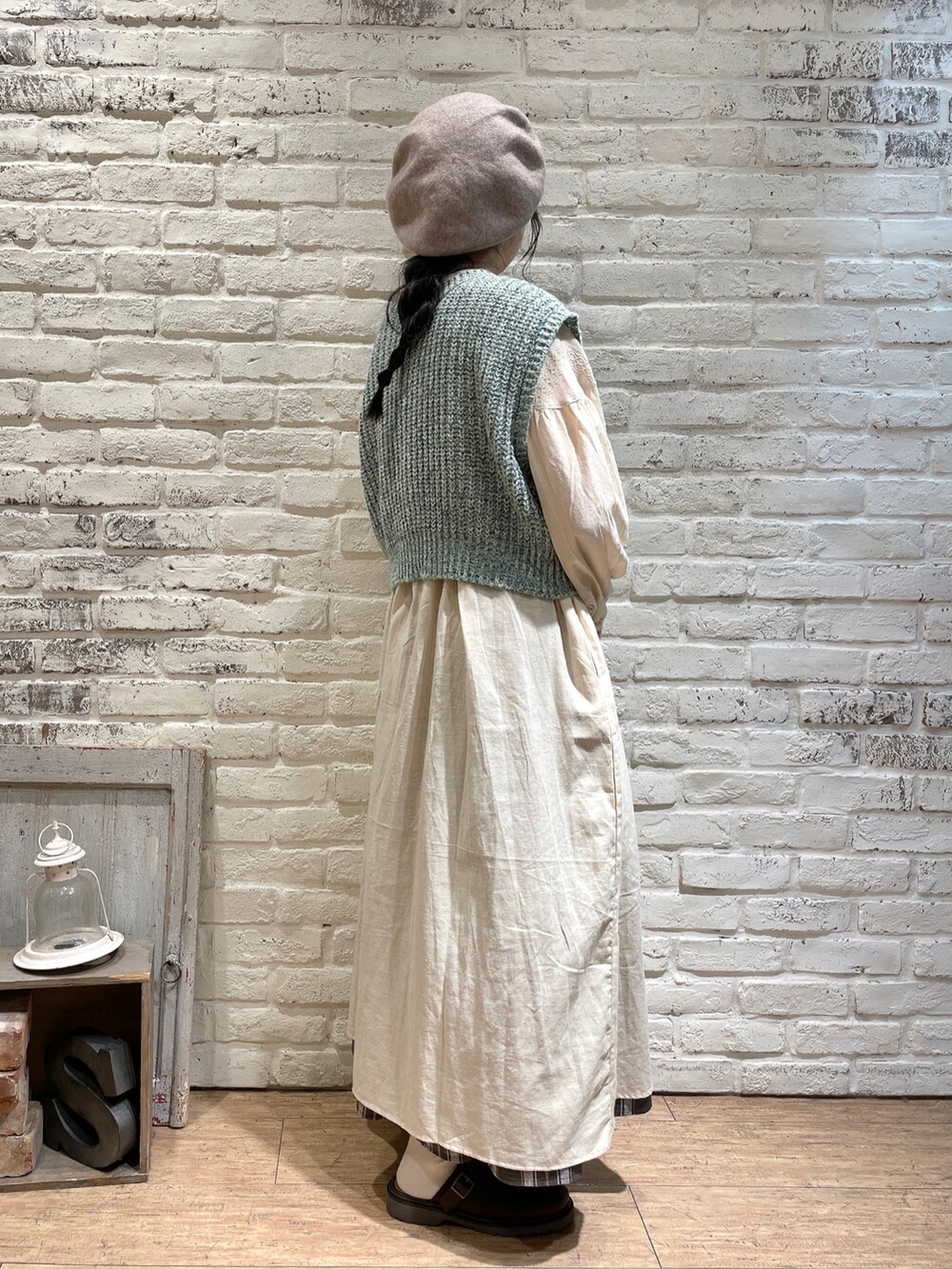 グリーン系のベスト、ブラック系のハンドバッグ、ブラウン系のワンピースを着用したレディースの秋コーディネートの2枚目の写真