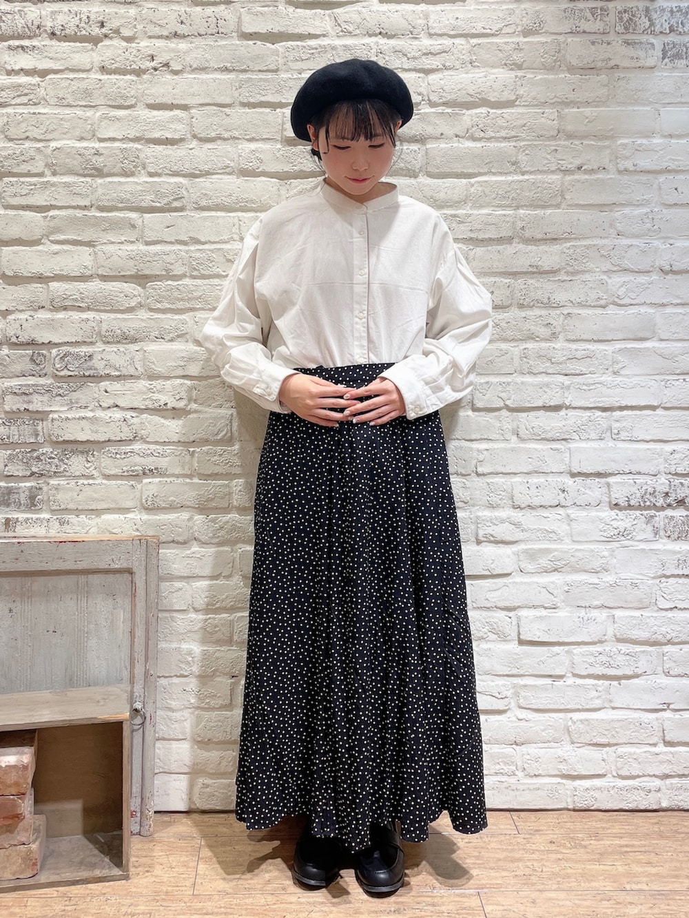 ホワイト系のチュニック、レッド系のカーディガン/ボレロ、ブラック系のスカートを着用したレディースの秋コーディネートの4枚目の写真