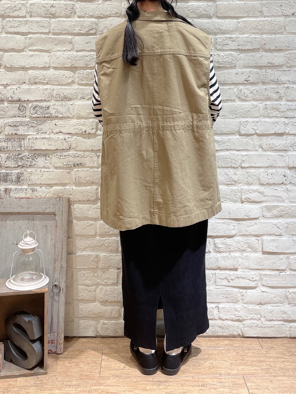 ベージュ系のベスト、ホワイト系のTシャツ/カットソー、ブラック系のスカートを着用したレディースの秋コーディネートの3枚目の写真