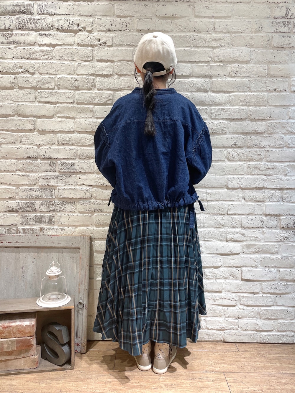 ブルー系のノーカラージャケット、ホワイト系のニット/セーター、グリーン系のスカートを着用したレディースの秋コーディネートの3枚目の写真