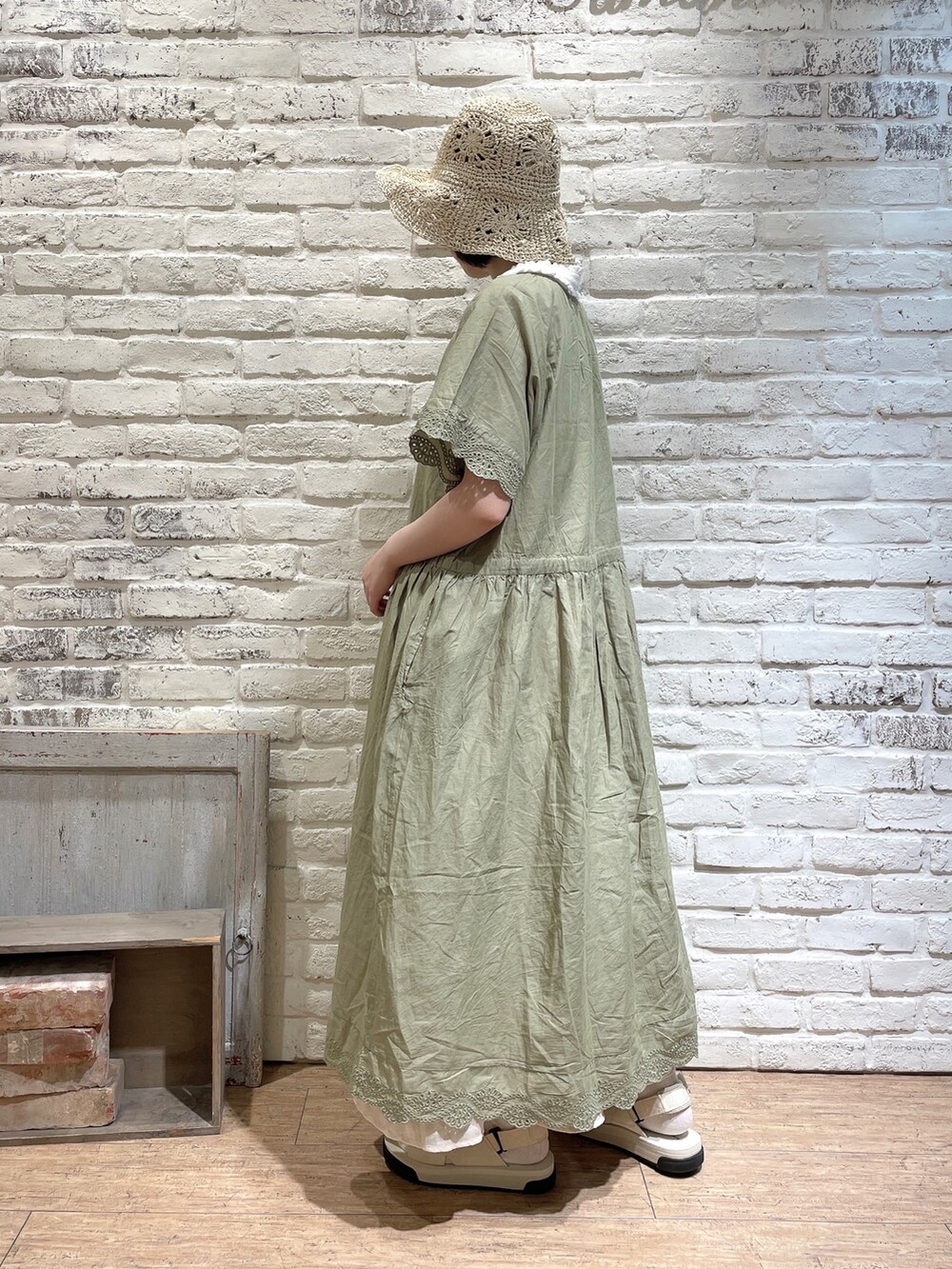 ベージュ系のトートバッグ、ホワイト系のサンダル、グリーン系のワンピースを着用したレディースの夏コーディネートの2枚目の写真