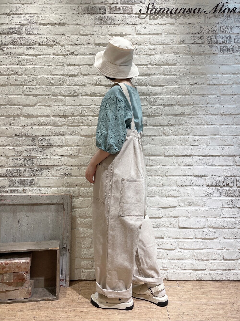 グリーン系のニット/セーター、ベージュ系のサロペット/オーバーオール、ホワイト系のサンダルを着用したレディースの夏コーディネートの3枚目の写真