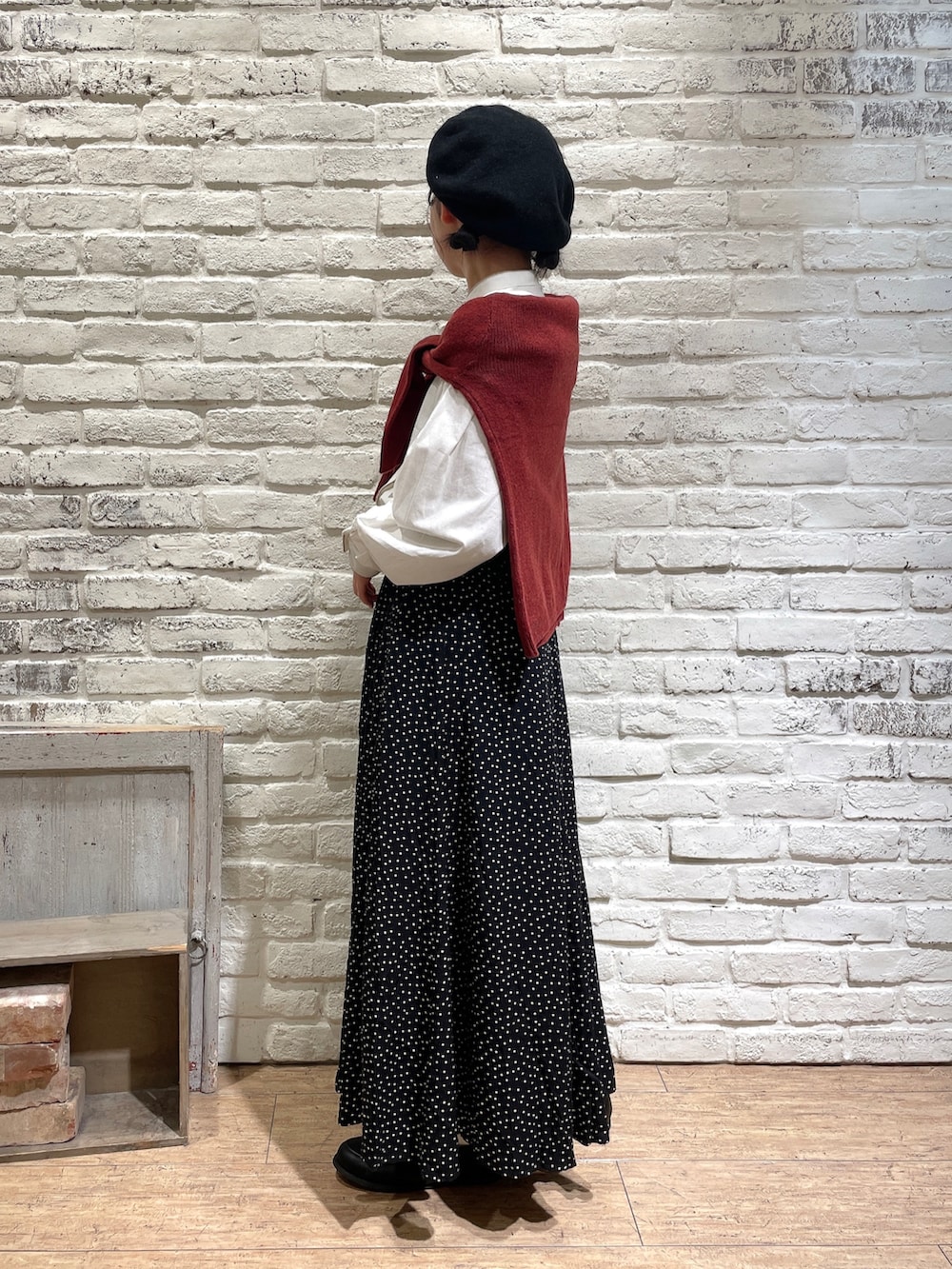 ホワイト系のチュニック、レッド系のカーディガン/ボレロ、ブラック系のスカートを着用したレディースの秋コーディネートの2枚目の写真