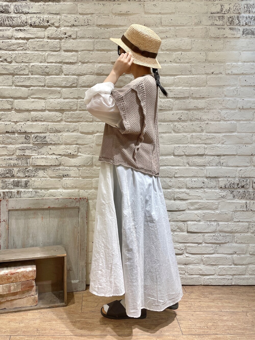 ブラック系のベスト、ホワイト系のワンピース、ベージュ系のハンドバッグを着用したレディースの春コーディネートの2枚目の写真