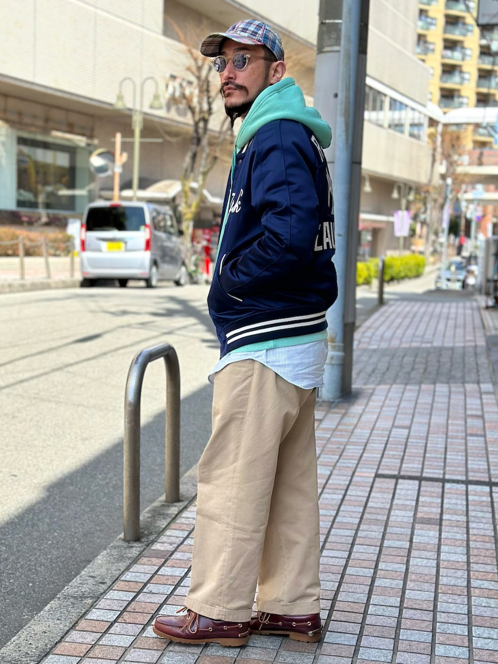 ブルー系のシャツ/ブラウス、グリーン系のパーカー、ブルー系のスタジャンを着用したメンズの春コーディネートの3枚目の写真