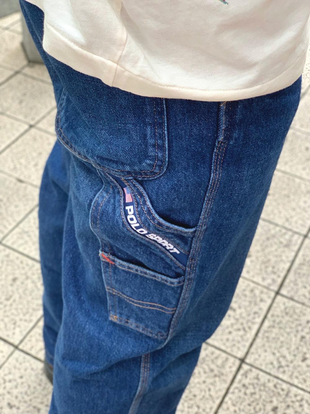 ホワイト系のTシャツ/カットソー、ブルー系のデニムパンツ、ブラウン系のブーツを着用したメンズの夏コーディネートの5枚目の写真