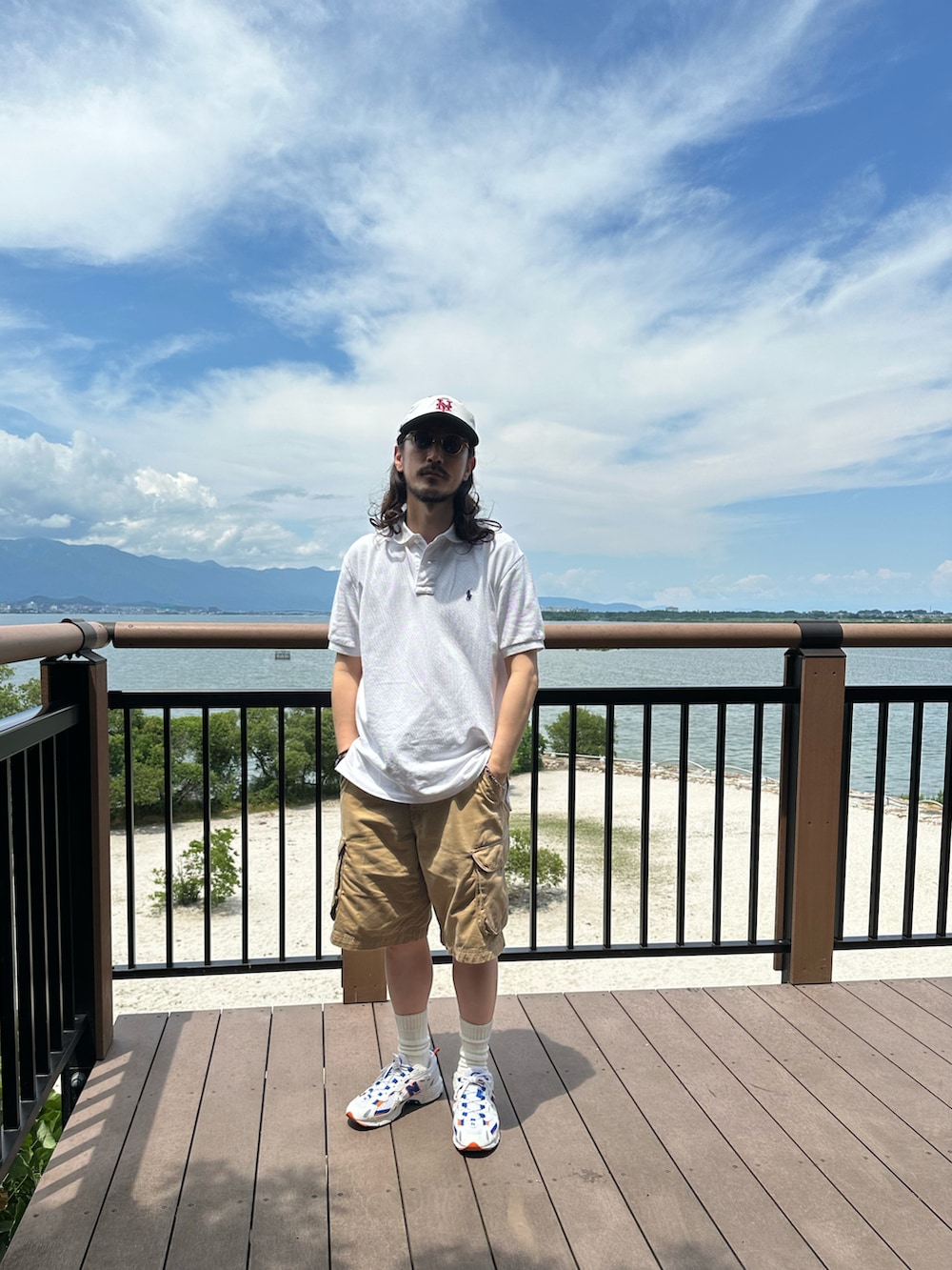 ホワイト系のポロシャツ、ブラウン系のカーゴパンツ、ホワイト系のスニーカーを着用したメンズの夏コーディネートの3枚目の写真