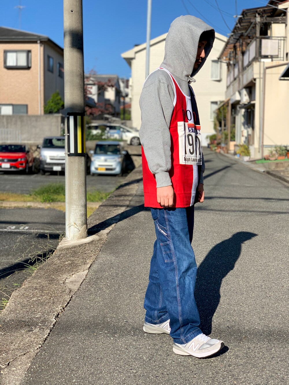 グレー系のパーカー、ホワイト系のタンクトップ、ブルー系のデニムパンツを着用したメンズの秋コーディネートの3枚目の写真