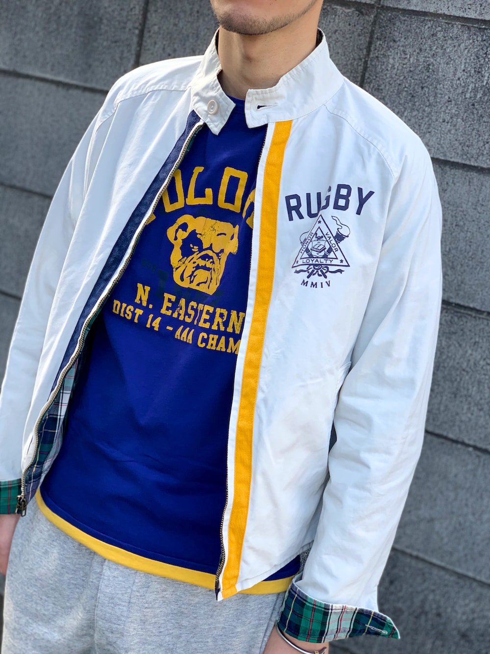 イエロー系のTシャツ/カットソー、ホワイト系のブルゾン、グレー系のパンツを着用したメンズの春コーディネートの2枚目の写真