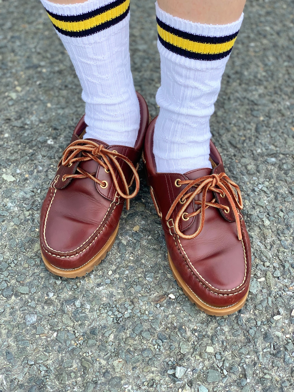 イエロー系のポロシャツ、グレー系のパンツ、レッド系のモカシン/デッキシューズを着用したメンズの夏コーディネートの5枚目の写真