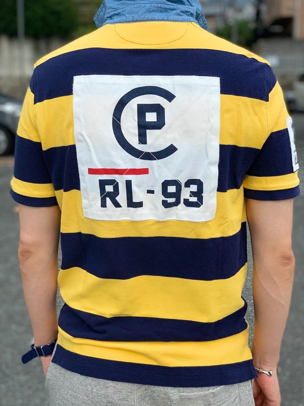 イエロー系のポロシャツ、グレー系のパンツ、レッド系のモカシン/デッキシューズを着用したメンズの夏コーディネートの3枚目の写真