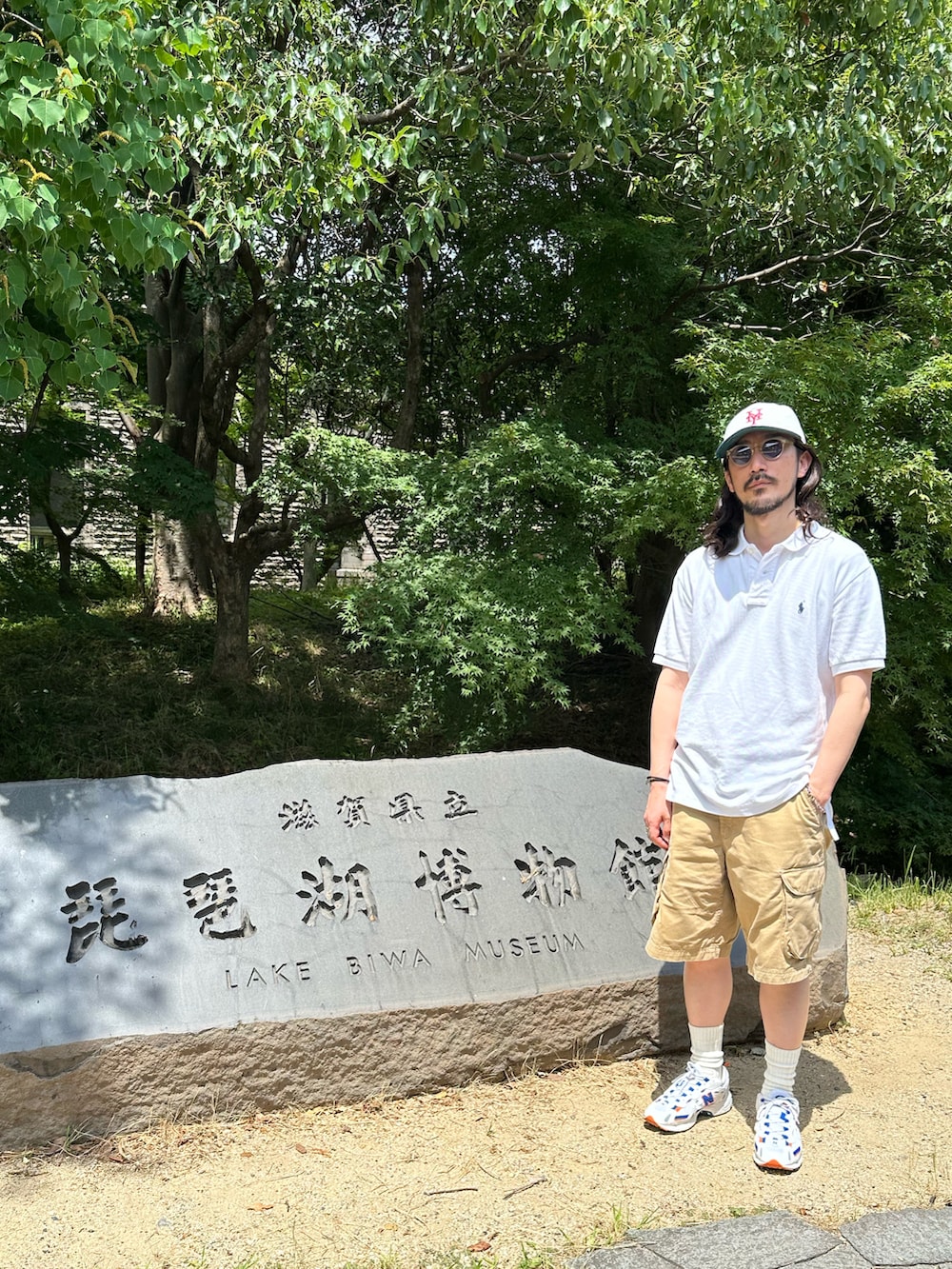 ホワイト系のポロシャツ、ブラウン系のカーゴパンツ、ホワイト系のスニーカーを着用したメンズの夏コーディネートの5枚目の写真