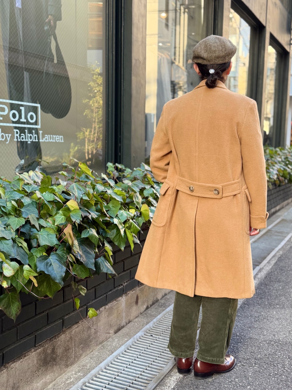 ベージュ系のシャツ/ブラウス、グリーン系のベスト、ブラウン系のチェスターコートを着用したメンズの冬コーディネートの2枚目の写真