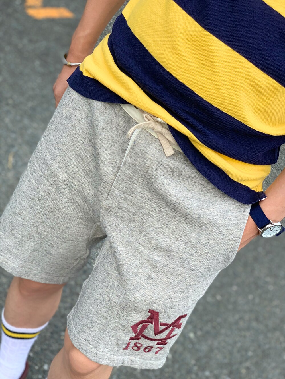 イエロー系のポロシャツ、グレー系のパンツ、レッド系のモカシン/デッキシューズを着用したメンズの夏コーディネートの4枚目の写真