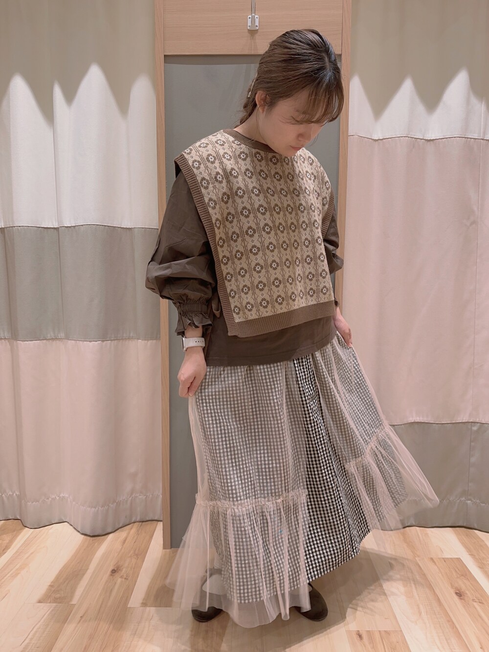 ブラウン系のベスト、ブラウン系のTシャツ/カットソー、ホワイト系のスカートを着用したレディースの秋コーディネートの2枚目の写真