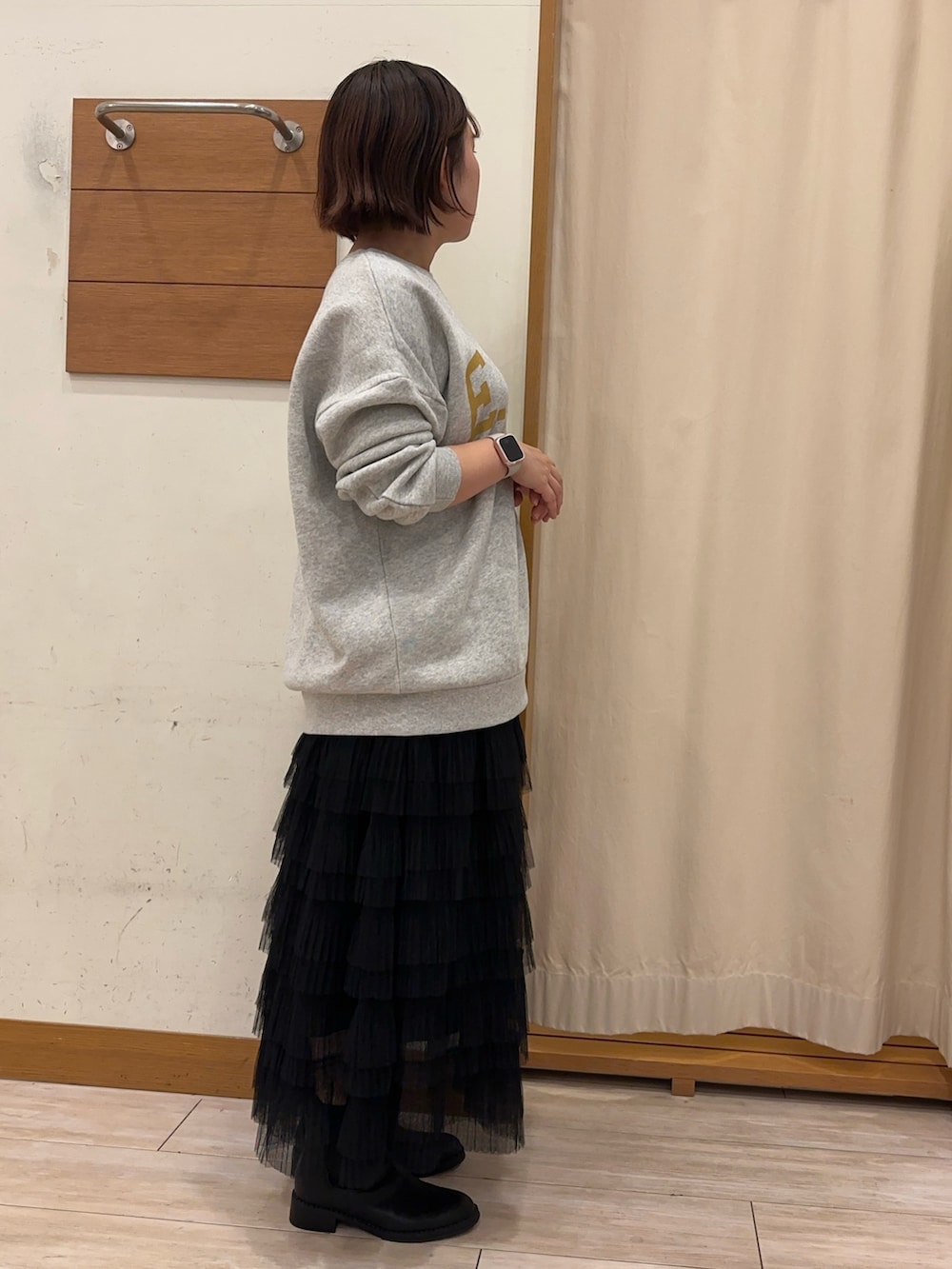 グレー系のスウェット、ブラック系のスカートを着用したレディースの秋コーディネートの2枚目の写真