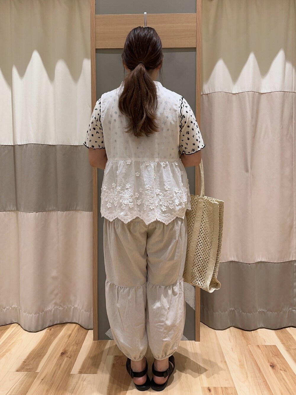 ホワイト系のベスト、ホワイト系のTシャツ/カットソー、ホワイト系のハンドバッグを着用したレディースの夏コーディネートの3枚目の写真