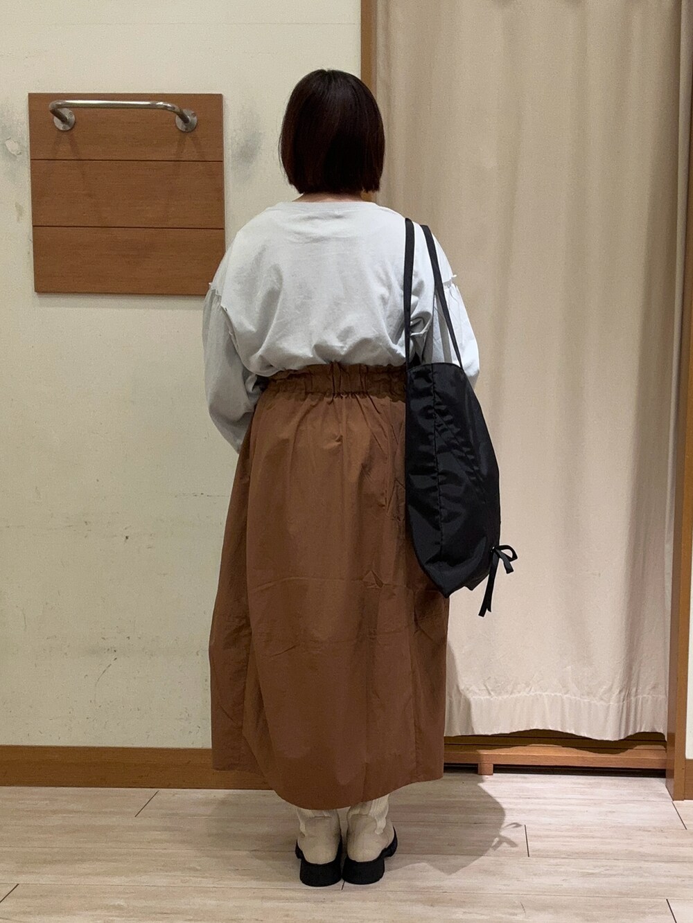 グレー系のTシャツ/カットソー、イエロー系のスカート、ホワイト系のブーツを着用したレディースの秋コーディネートの3枚目の写真