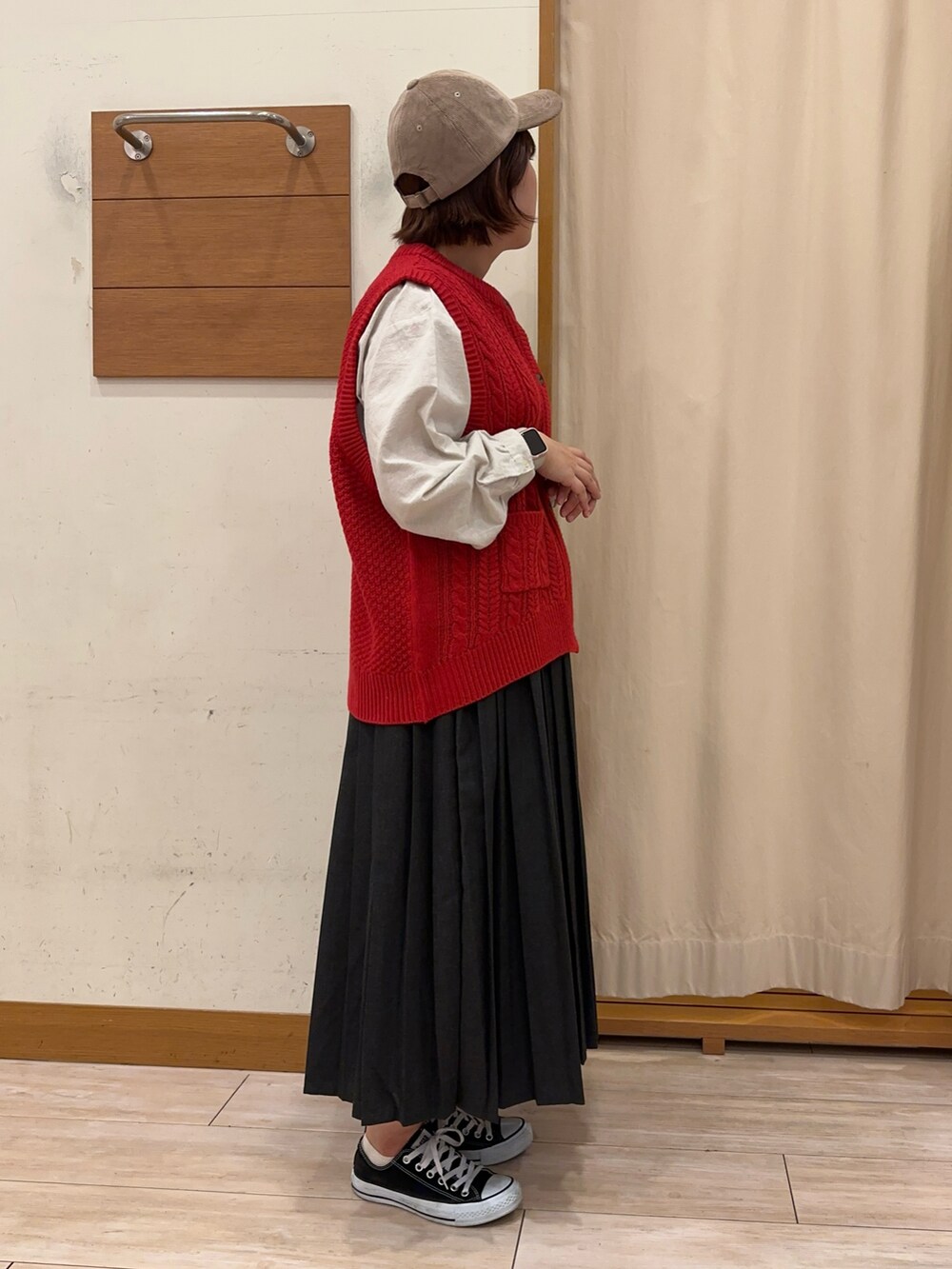 レッド系のベスト、ホワイト系のシャツ/ブラウス、グレー系のスカートを着用したレディースの秋コーディネートの2枚目の写真