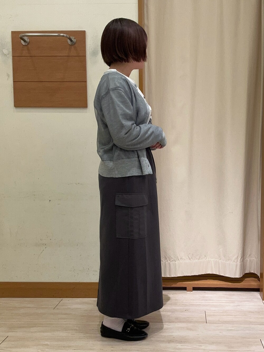 グレー系のカーディガン/ボレロ、ホワイト系のTシャツ/カットソー、グレー系のスカートを着用したレディースの秋コーディネートの2枚目の写真