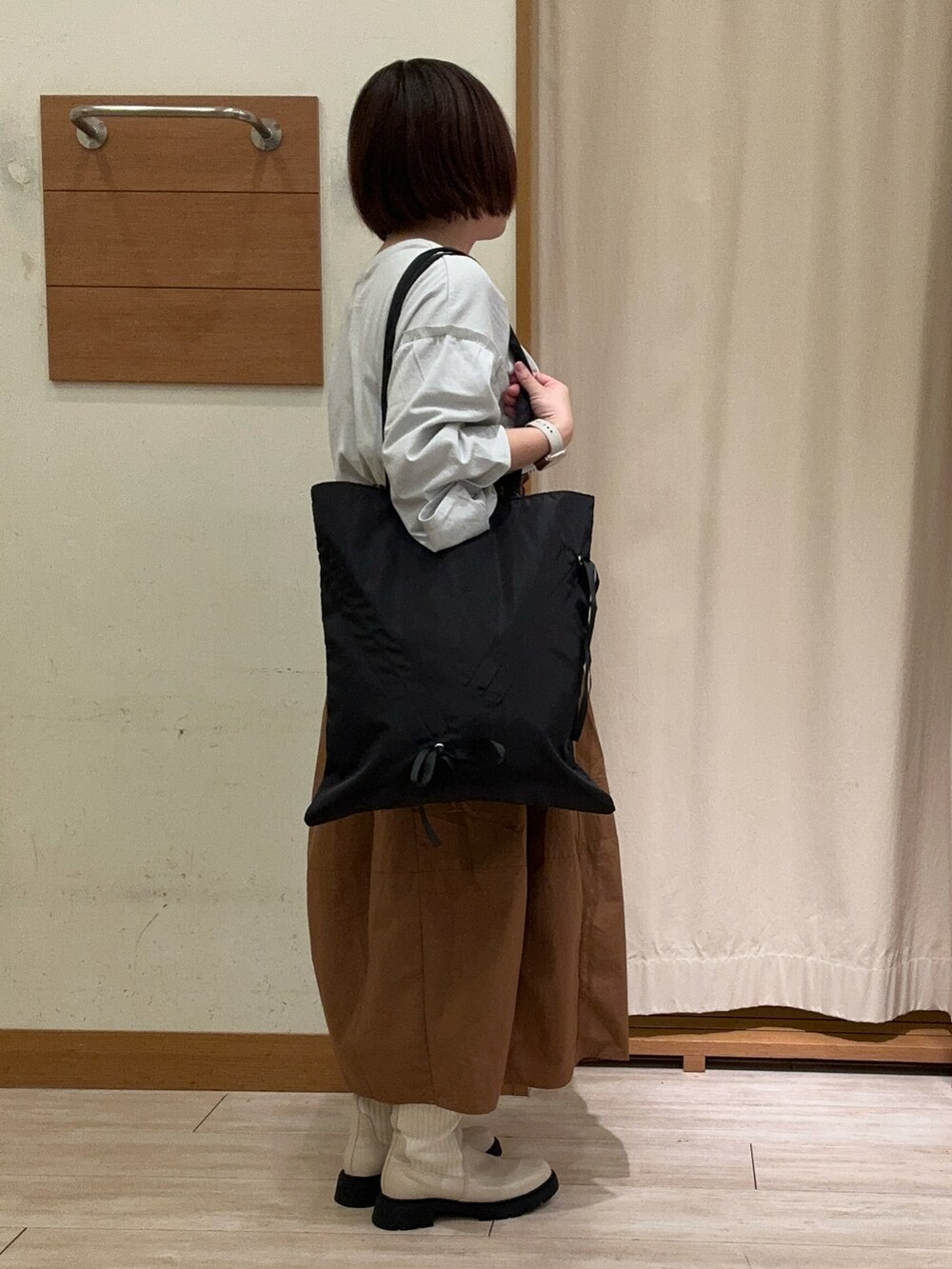 グレー系のTシャツ/カットソー、イエロー系のスカート、ホワイト系のブーツを着用したレディースの秋コーディネートの2枚目の写真