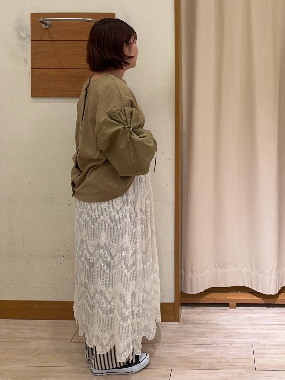 グリーン系のTシャツ/カットソー、ホワイト系のスカート、ホワイト系のパンツを着用したレディースの秋コーディネートの2枚目の写真