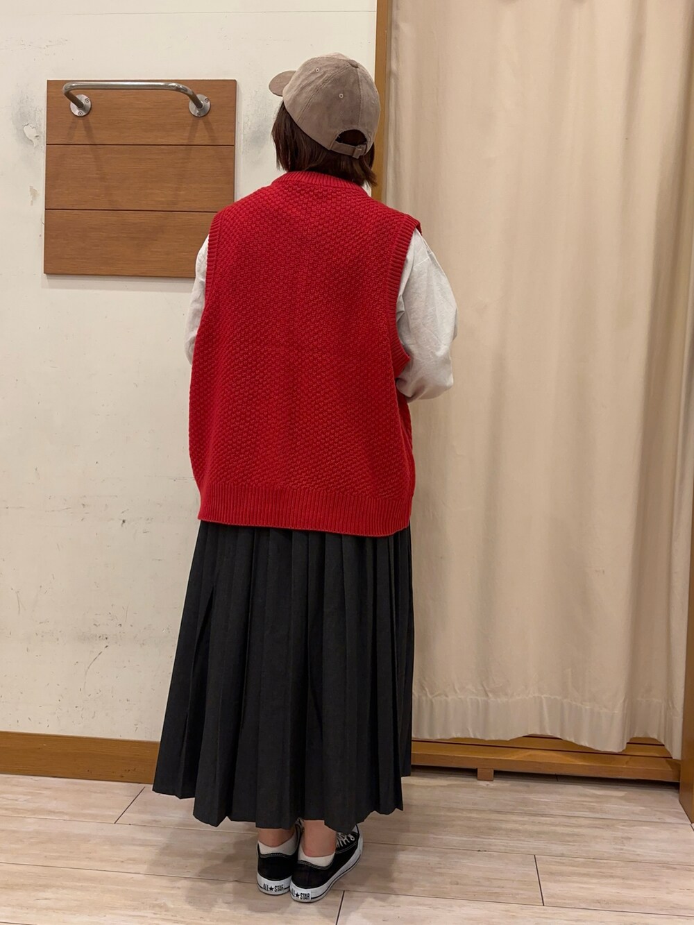 レッド系のベスト、ホワイト系のシャツ/ブラウス、グレー系のスカートを着用したレディースの秋コーディネートの3枚目の写真