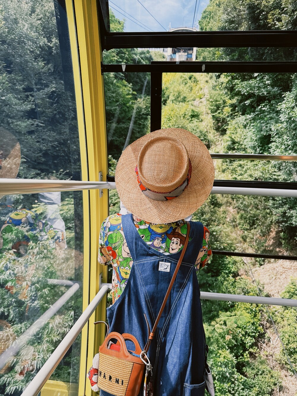 ベージュ系のショルダーバッグ、ブルー系のサロペット/オーバーオール、ブラック系のサンダルを着用したレディースの秋コーディネートの3枚目の写真